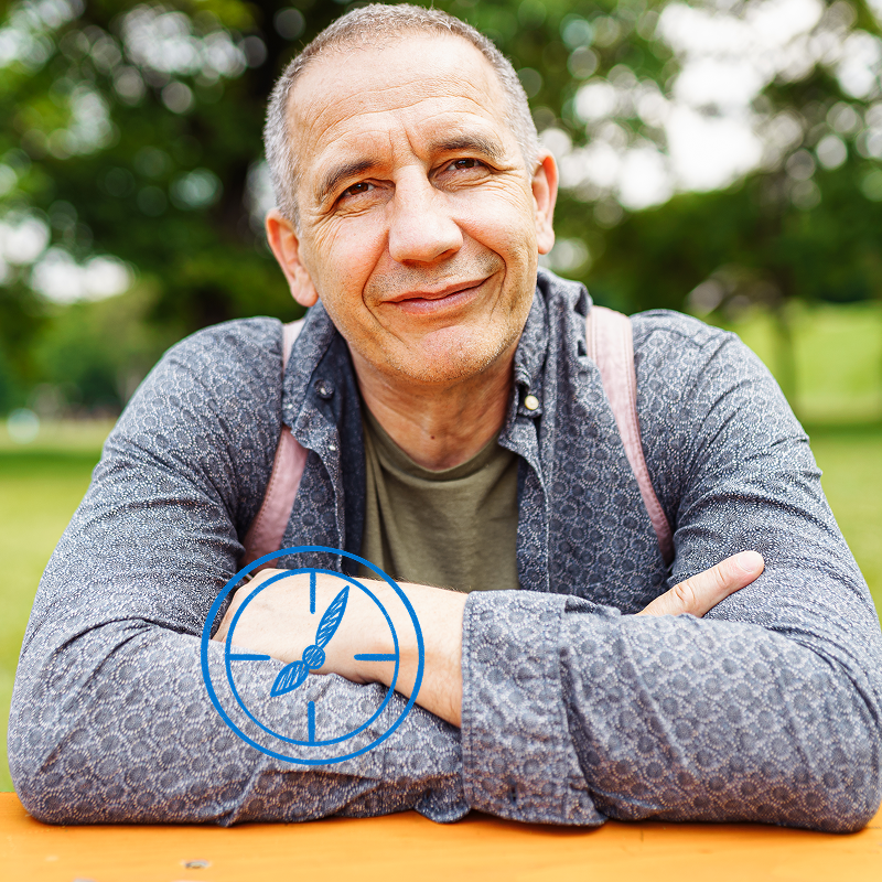 Man looking at the camera while sitting at the picnic table