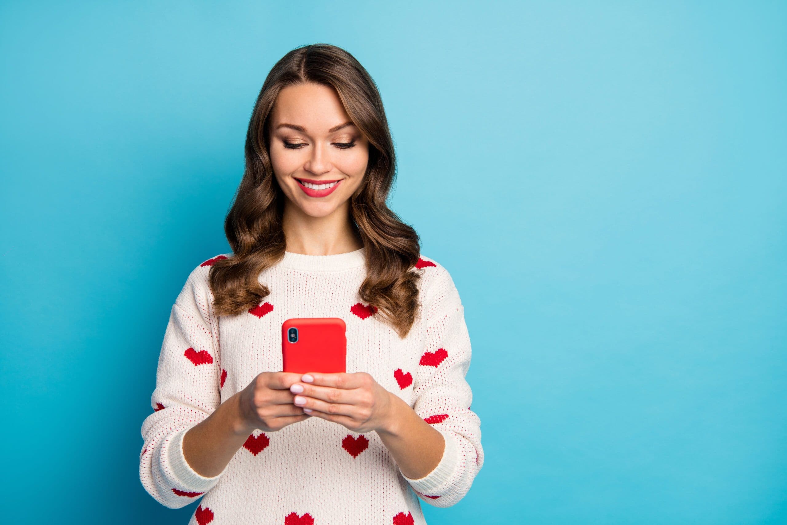Lady wearing heart sweater, holding mobile smiling