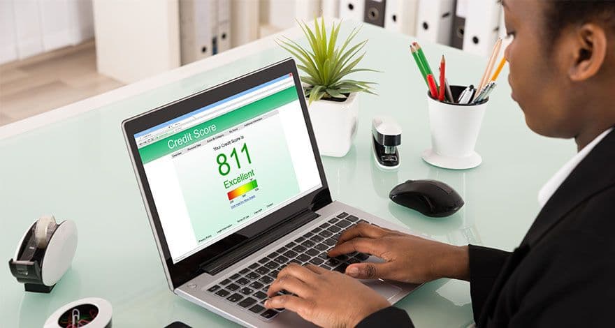 Person using a laptop on a glass desk displaying an excellent credit score of 811