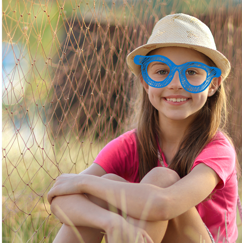 Person in pink shirt and straw hat sitting cross-legged near netting and greenery, face blurred