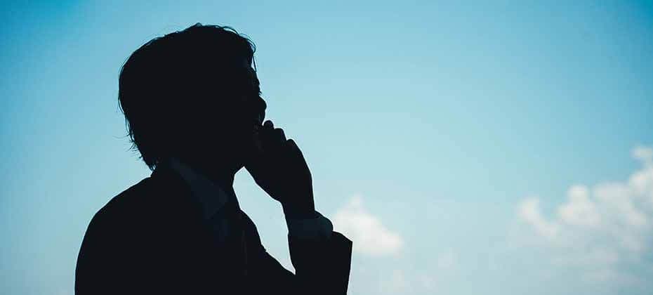 Silhouette of a man on the phone against a clear sky representing a sole trader researching business loan options