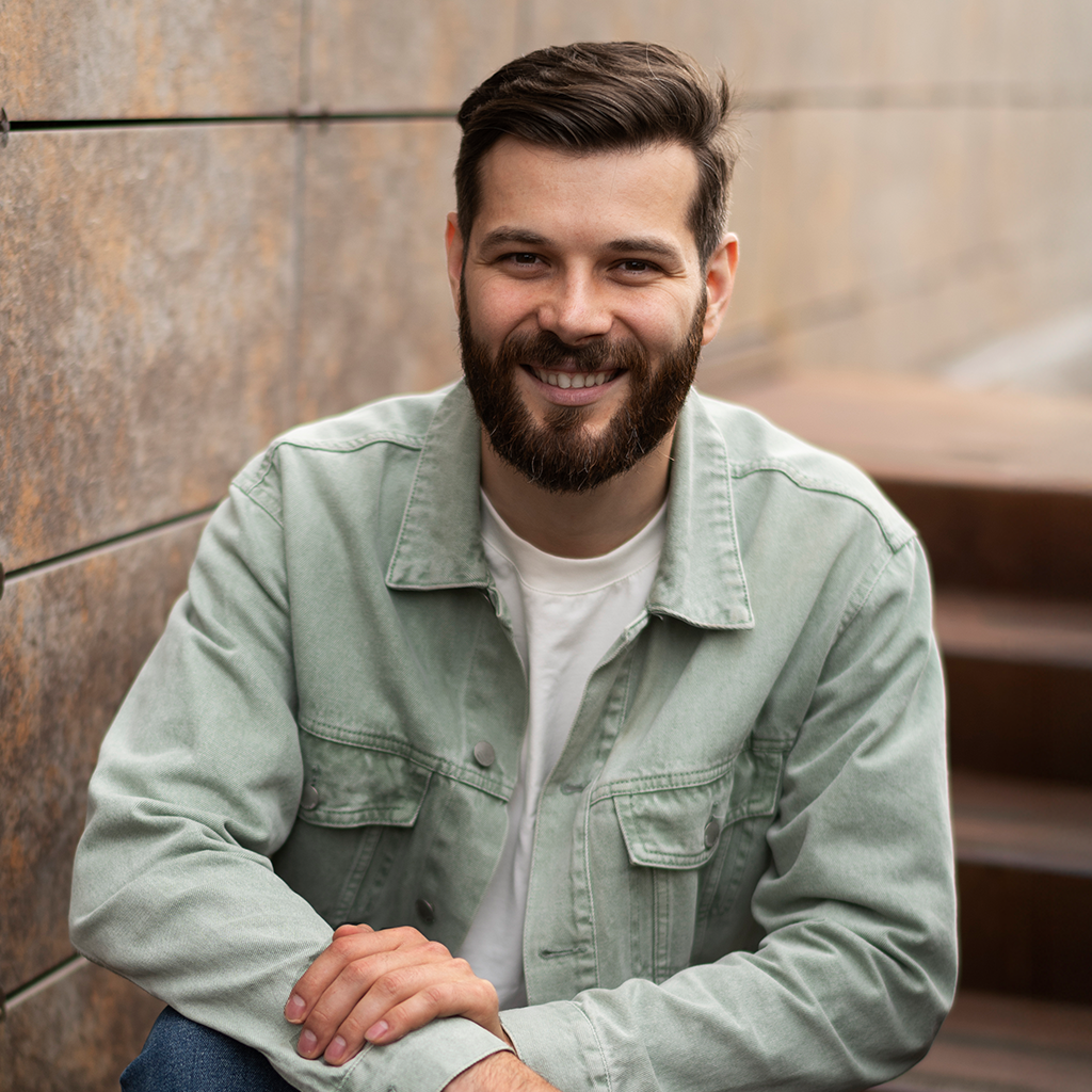 Person in a light green jacket sitting on wooden stairs next to a tiled wall