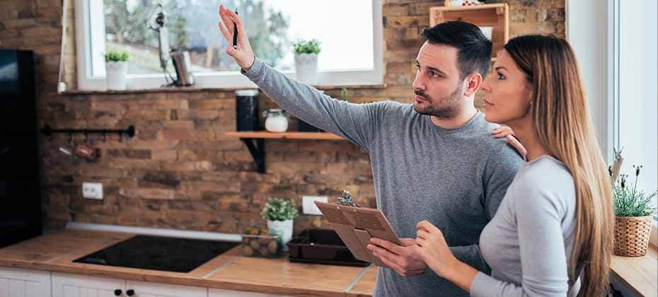 Couple planning kitchen upgrades with clipboard in hand exploring home renovation loan financing options
