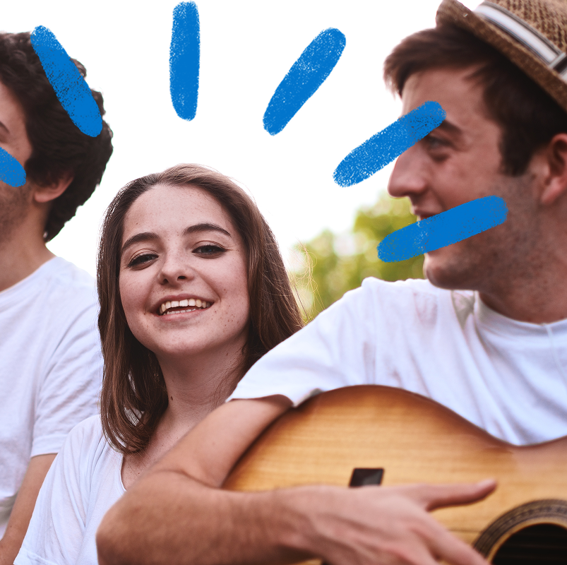 Young woman smiling while listening her colleague playing guitar