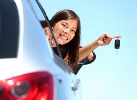 Woman holding car keys with head outside of the car window