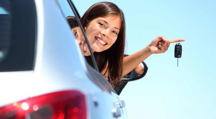 Woman holding car keys with head outside of the car window