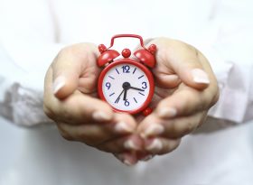 Hands holding a mini clock