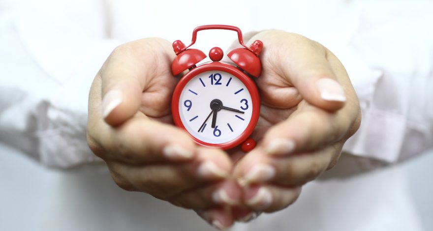 Hands holding a mini clock