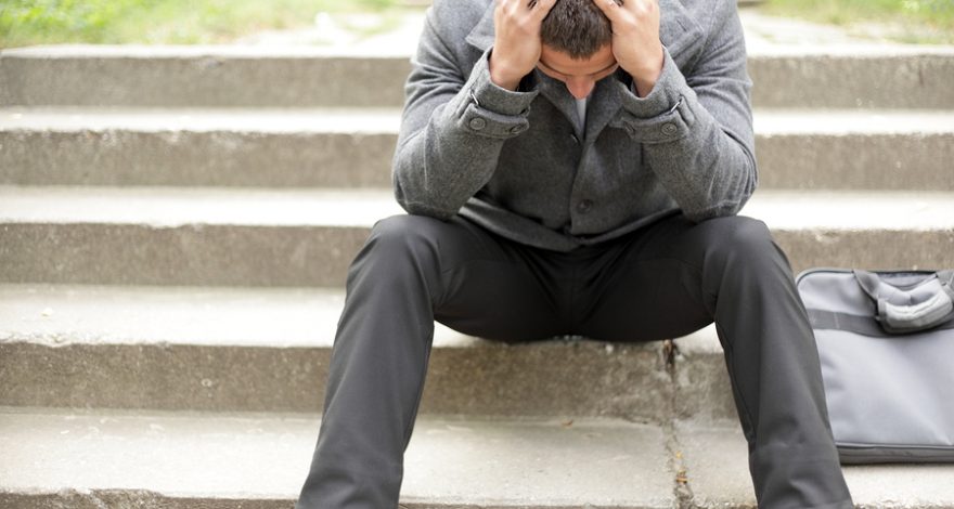 Man stressed with both hands on head