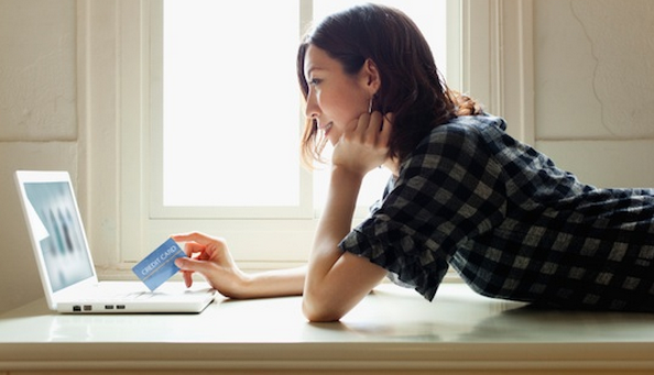 Women lying on the floor with credit card with a laptop