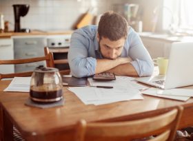 Stressed man with paper bills on table