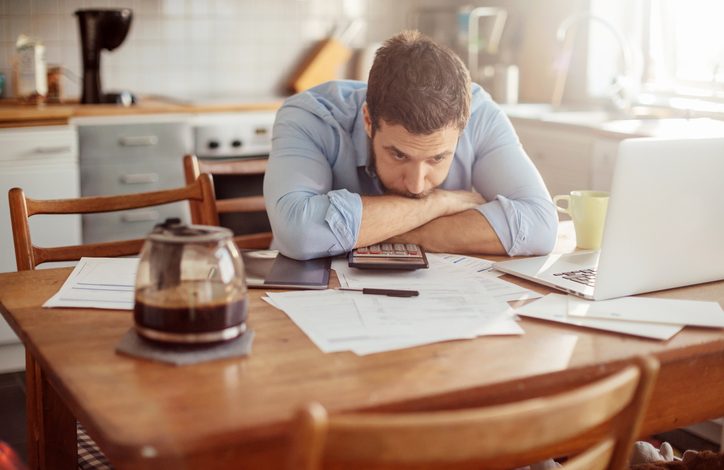 Stressed man with paper bills on table