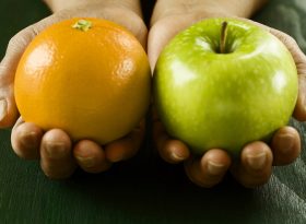 A pair of hands holding apple and orange
