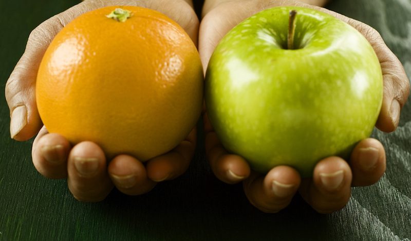 A pair of hands holding apple and orange