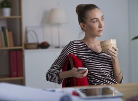 A woman holding a glass and thinking