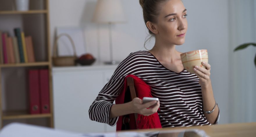 A woman holding a glass and thinking