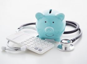 Piggy bank, calculator and Stethoscope on table