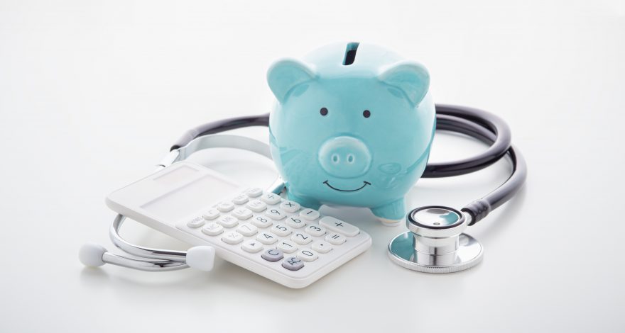 Piggy bank, calculator and Stethoscope on table