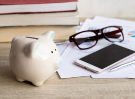 Expenses and piggy bank on table