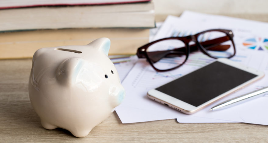 Expenses and piggy bank on table